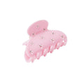 Pink hair clip with decorative elements on a white background