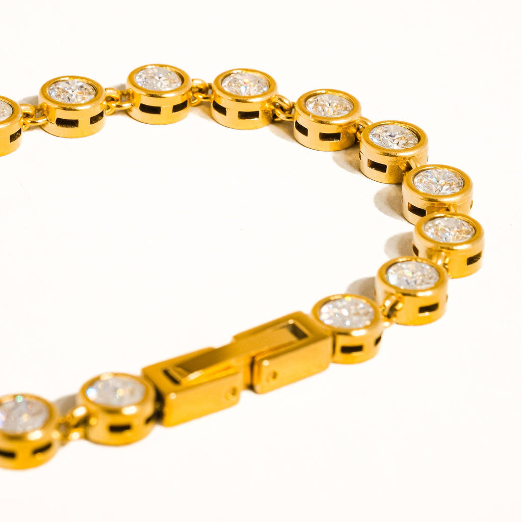 Gold bracelet with diamond-like stones on a white background